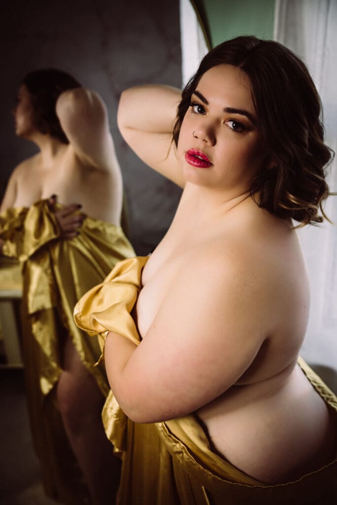 an empowered women looks confidently into the camera posing with a gold sheet near columbia