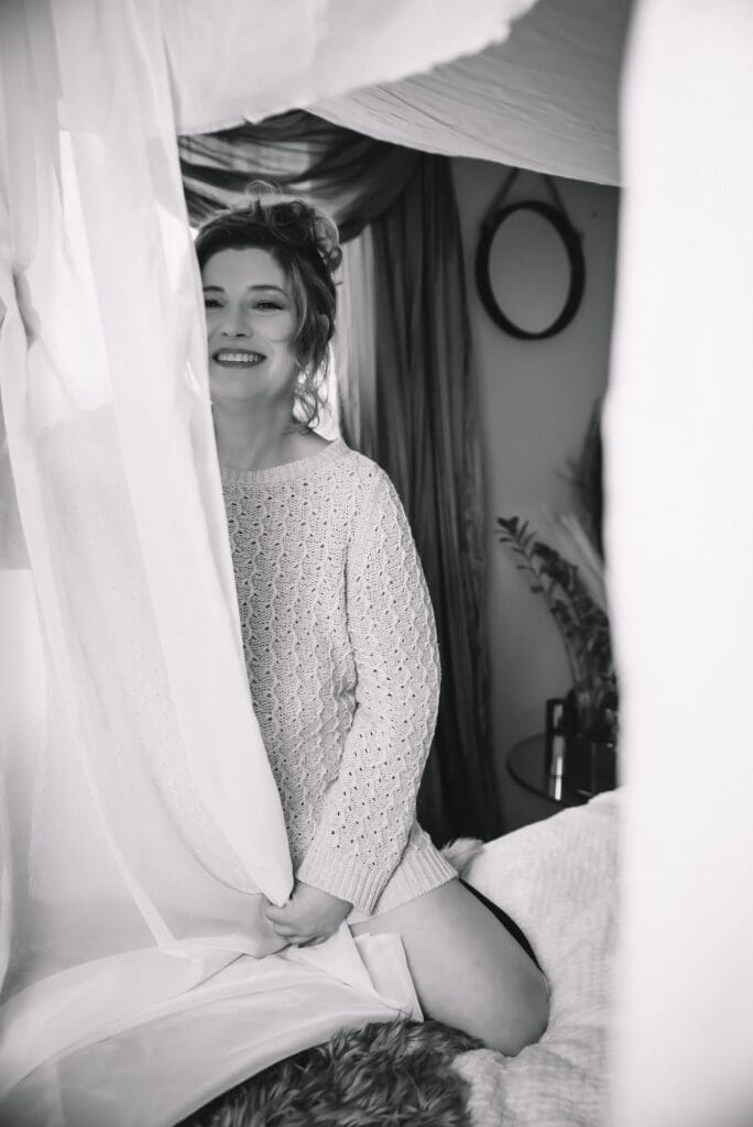 a smiling woman poses on a canopy bed