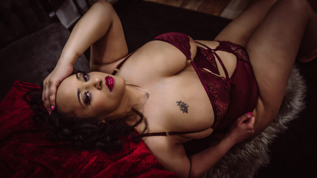 a woman poses confidently in a bare elegance boudoir session with red accents