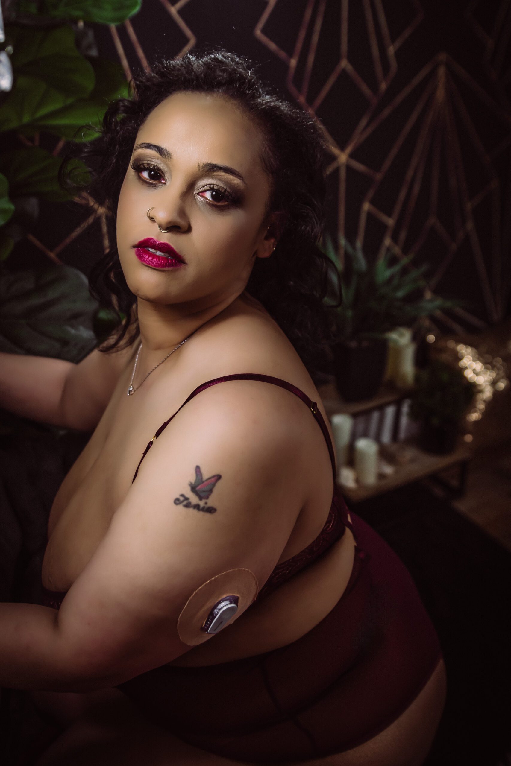a woman with a butterfly tattoo and an insulin pump poses for a boudoir photo