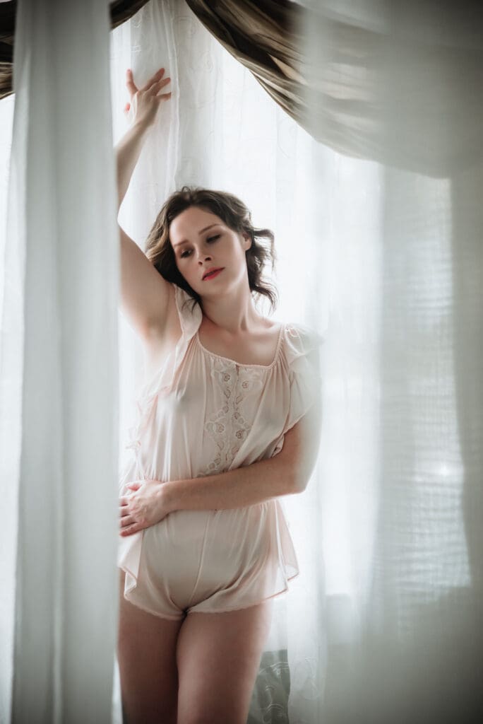 a boudoir photography session with flowing white fabric and muted tones
