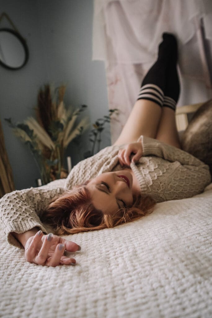 a woman poses on a bed showing off her beautiful fingernails