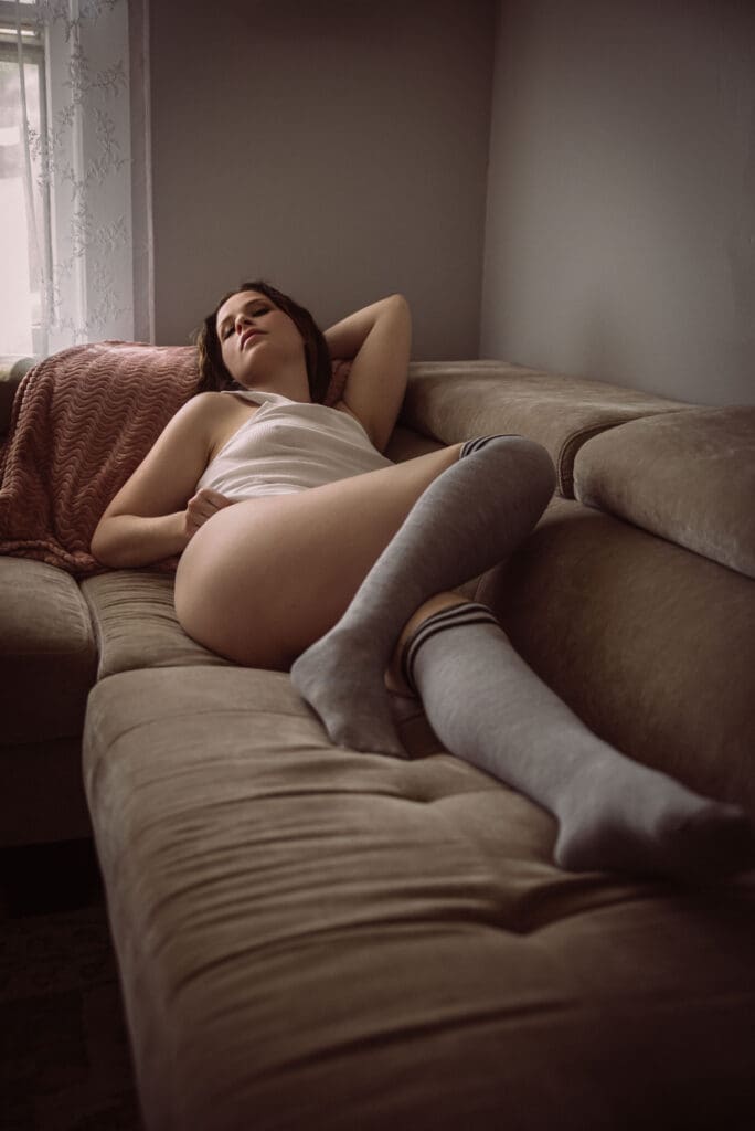 a woman reclines on a tan couch wearing high grey socks