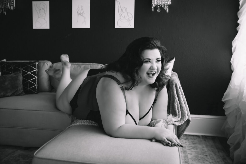 a black and white image of a plus size boudoir guest smiling at bare elegance