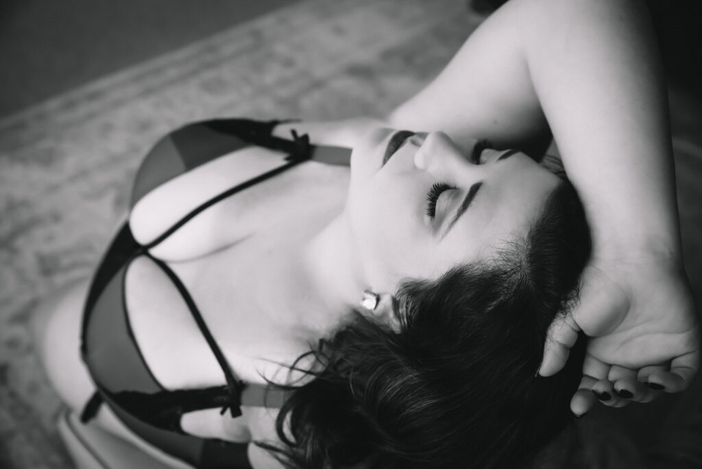 a black and white image of a woman leaning back in strappy lingerie
