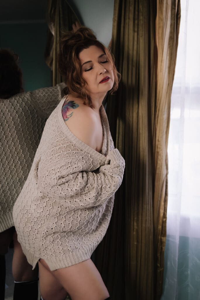 a woman reveals a shoulder tattoo in a boudoir photoshoot near columbia sc